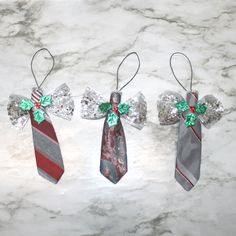 three christmas tie ornaments hanging from the side of a marble counter top with green and red bows on them