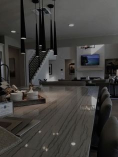 a large kitchen with marble counter tops and black pendant lights hanging from it's ceiling