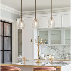 a kitchen with marble counter tops and gold bar stools next to a chandelier