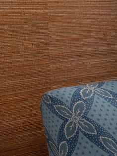 an upholstered blue and white chair next to a wall with wood slats