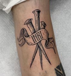 a tattoo on the leg of a man with two crossed swords and an iri ribbon