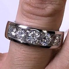 a woman's hand with a wedding ring that has five diamonds on it and two fingers