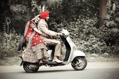 a man and woman riding on the back of a scooter