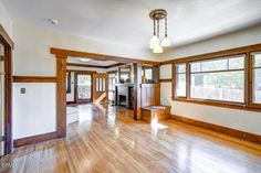 an empty living room with hard wood floors and large windows in the center, along with wooden paneling