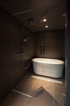 a bathroom with a bathtub and shower head in the corner next to it is illuminated by recessed lights