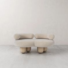 two white couches sitting next to each other on top of a cement floor in front of a wall