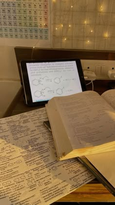 an open book sitting on top of a table next to a tablet computer and keyboard