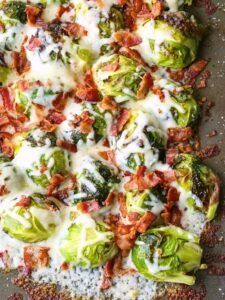 a pizza with cheese, bacon and broccoli on it sitting on a pan