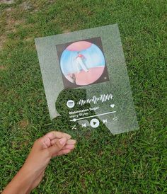 someone is holding up a sign in the grass to show off it's artwork