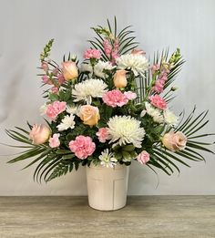 a white vase filled with lots of pink and white flowers