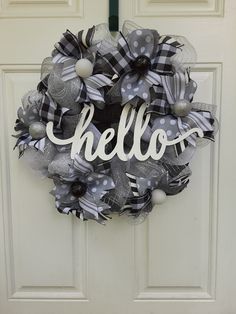 a wreath with the word hello on it hanging from a front door decorated with silver and black mesh