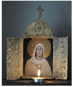 a candle is lit in front of an image of the virgin mary