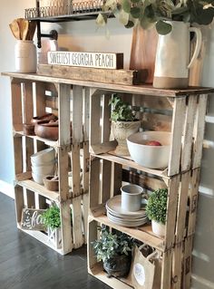 a wooden shelf filled with plates and bowls on top of a hard wood floor next to a potted plant