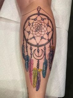 a woman's leg with a tattoo on it that has a dream catcher in the middle