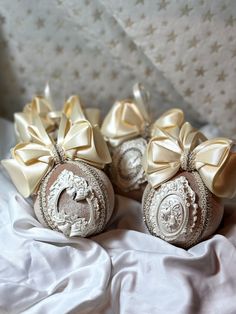 four ornaments with bows on them sitting on a bed