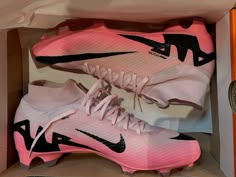 a pair of pink and black nike shoes in a box with the shoe laces down