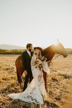 a bride and groom standing next to a horse in the middle of an open field