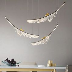 three lights hanging from the ceiling above a dining room table with grapes and fruit on it