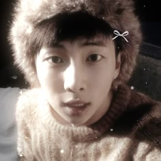 a young man wearing a fur hat and scarf with stars on it's side