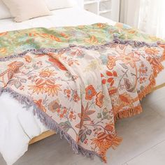 a white bed with an orange and green blanket on it