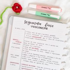 a notebook with some writing on it next to a red flower and two markers that say segundraa fose moderno