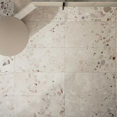 an overhead view of a tiled floor with a round table in the middle and a circular mirror above it