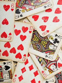 a pile of playing cards with red and black hearts on the sides, all in different shapes and sizes