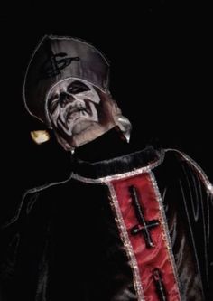 a man dressed up as a skeleton wearing a priest's robe and holding a cross