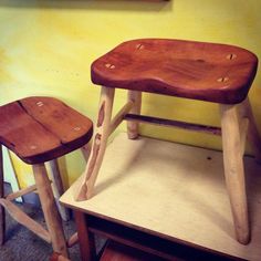 two wooden stools sitting next to each other in front of a painting on the wall