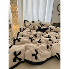 a bed with black and white comforters on top of it in front of a window