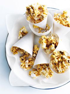 small cones filled with popcorn sitting on top of a white plate