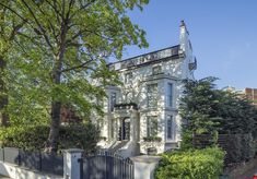 a large white house sitting next to a lush green park