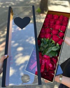 a person holding a box with roses in it and a heart cut out on the side