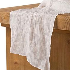 a wooden bench with a white blanket hanging from it's back end and on top of the table