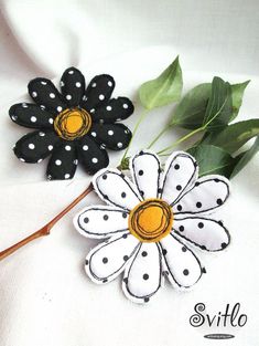 two black and white flower brooches sitting next to each other