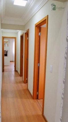 an empty hallway with wooden doors and hard wood flooring on either side of the room