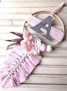 a pink and silver decoration with flowers on the hoop next to it is a monogrammed letter