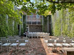 an outdoor dining area with tables and chairs set up in front of a brick building