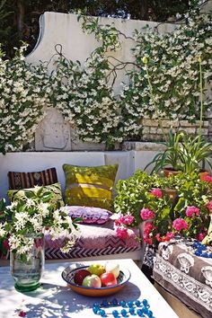 an outdoor seating area with flowers and fruit on the table