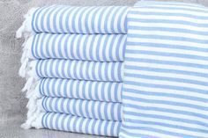 blue and white striped towels stacked on top of each other in front of a gray wall