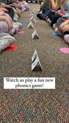 a group of kids sitting on the floor playing with paper boats and arrows that read watch us play a fun new phonics game