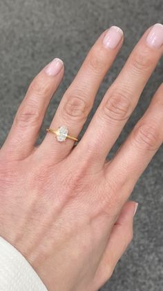 a woman's hand with a diamond ring on top of her left hand, in front of a carpeted area