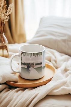 a white coffee cup sitting on top of a wooden tray next to a bed covered in blankets