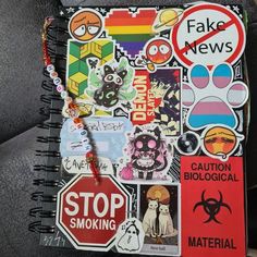 a notebook covered in stickers and magnets sitting on a chair next to a pillow