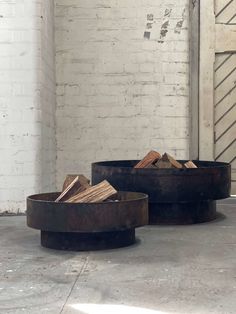 three metal bowls sitting on top of a cement floor next to a white brick wall