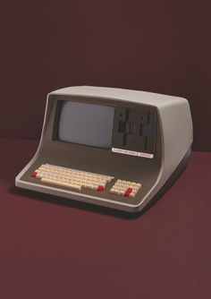 an old computer sitting on top of a red table next to a black and white keyboard