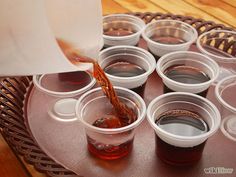 a tray filled with cups and sauce being poured into them on top of each other