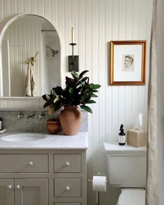 a bathroom with a sink, toilet and mirror in it's corner area is shown