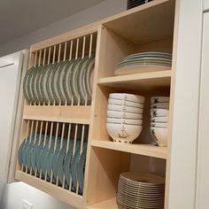 plates and bowls are stacked on shelves in the kitchen