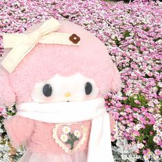 a pink stuffed animal with a scarf around it's neck in front of flowers